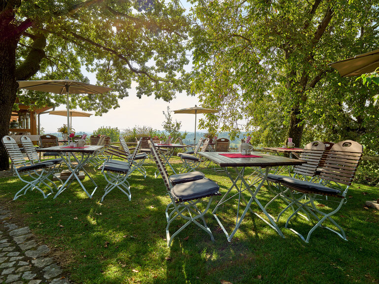 Schöner Blick auf den gemütlichen Biergarten des Hotel Anetseder mit einem hellen Sonnenuntergang im Hintergrund.