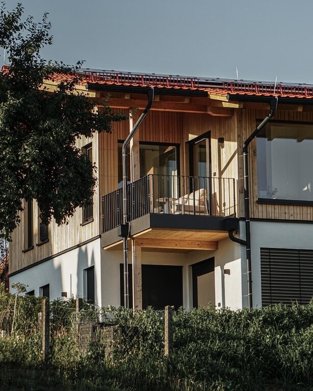 Die Außenansicht eines Spa Lofts des Golf- und Landhotels Anetseder zeigt sich im warmen, goldenen Licht der Abendsonne.