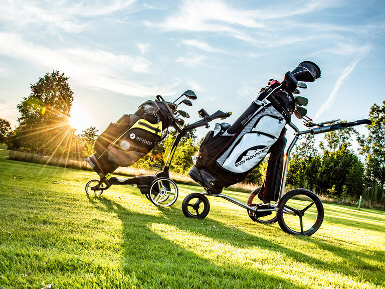 Ein Golfer ist mit seinem Golftrolley auf der Golfanlage des Hotel Anetseder unterwegs.