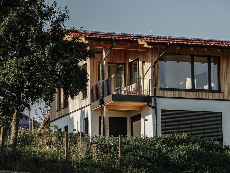 Die Außenansicht eines Spa Lofts des Golf- und Landhotels Anetseder zeigt sich im warmen, goldenen Licht der Abendsonne.