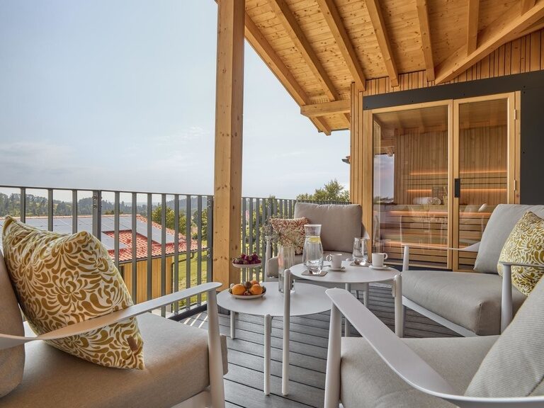 Eine gemütlich gestaltete Terrasse im Spa-Lofts-Bereich mit bequemen Sofas, stilvollen Stühlen und einer modernen Sauna lädt zum Entspannen ein.