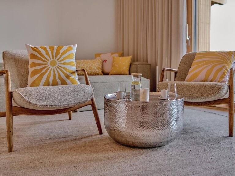 Ein harmonisch gestaltetes Wohnzimmer mit zwei Clubsesseln und Kaffeetisch schafft in den Spa Lofts des Hotel Anetseder eine behagliche Wohlfühlatmosphäre.
